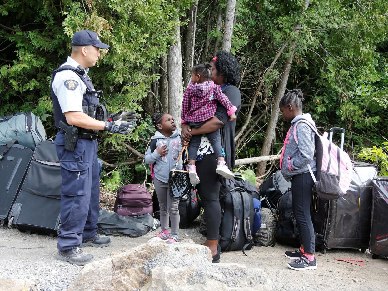 A family who identified themselves as from Haiti are confronted by a Royal Canadian Mounted Police (RCMP) officer as they try to enter into Canada the US: REUTERS/Christinne Muschi