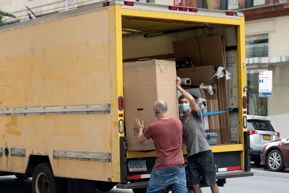 People wearing masks load a box into a moving truck as the city continues Phase 4 of re-opening following restrictions imposed to slow the spread of coronavirus on August 31, 2020, in New York City. (Photo by Alexi Rosenfeld/Getty Images)