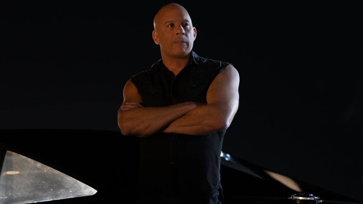  Vin Diesel staring off camera while leaning against a car at night in Fast X. 