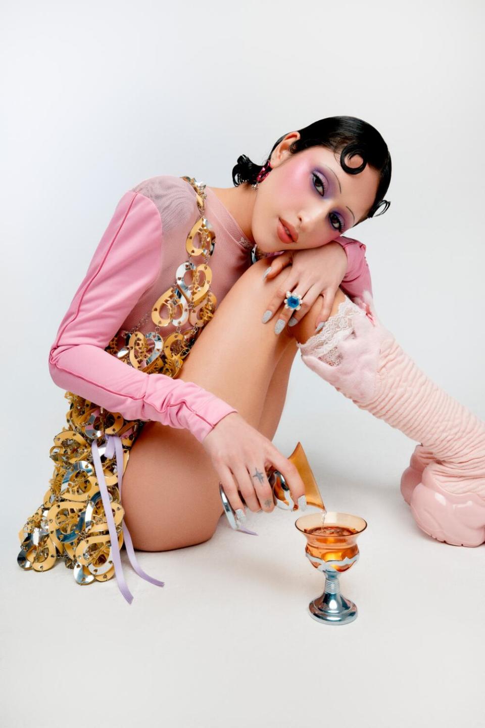 A woman wearing pink pours a glass into another glass.