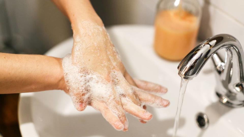 Hands being washed under water with soap