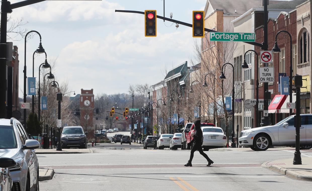 A pedestrian crosses Front Street at Portage Trail in the heart of a proposed Designated Outdoor Refreshment Area in Cuyahoga Falls. The proposed DORA runs along Front Street from Moe's Restaurant on the north end to HiHO Brewing Co. on south end.