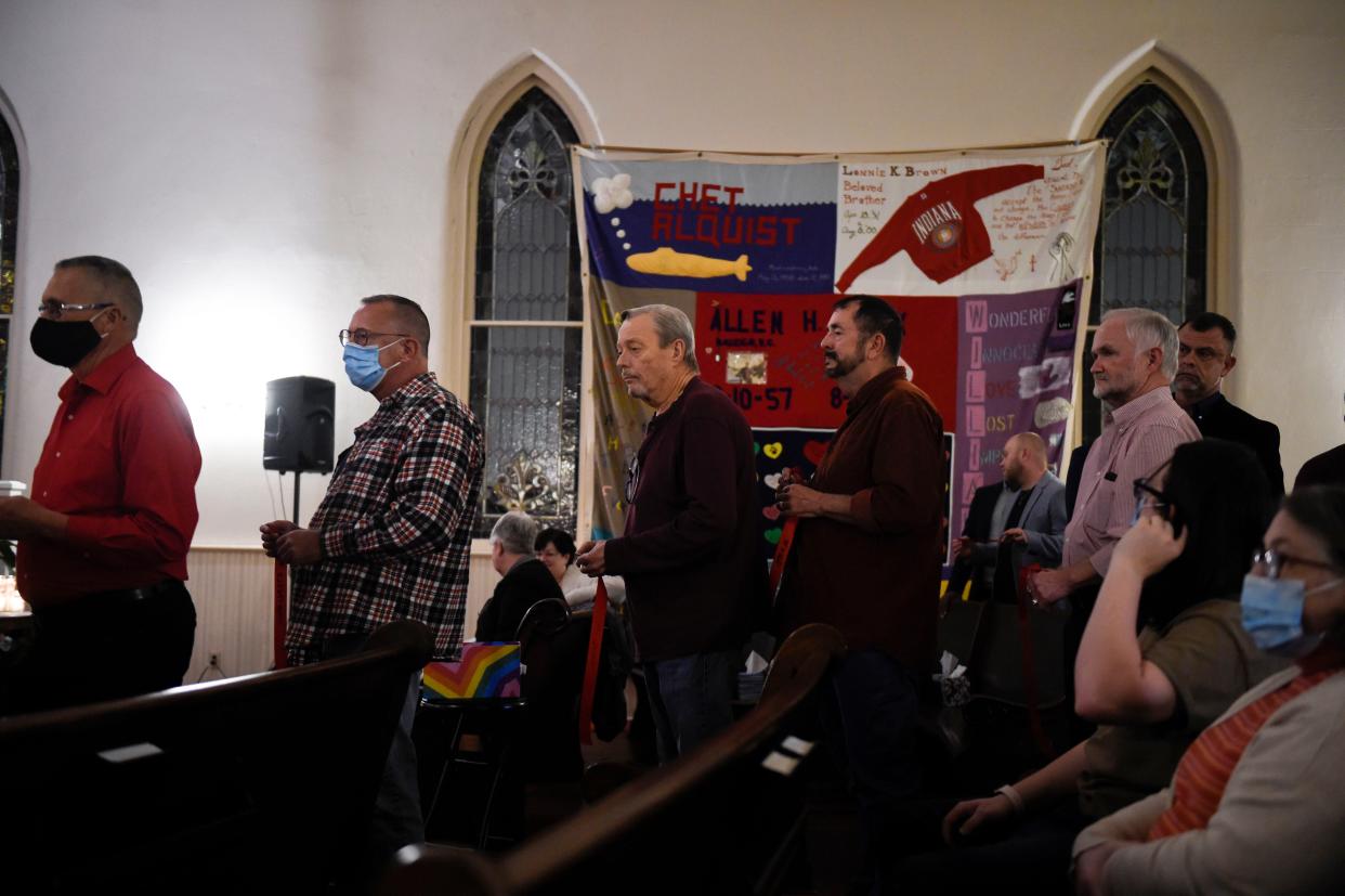 People come forward to pin a red ribbon to the red wreath during the World AIDS Day remembrance service at the Metropolitan Community Church in Augusta on Wednesday.