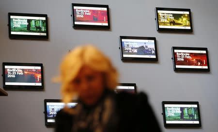 A woman walks in front of screens at the 'Berlinale Palace' promoting the upcoming 66th Berlinale International Film Festival in Berlin, Germany, February 10, 2016. REUTERS/Fabrizio Bensch