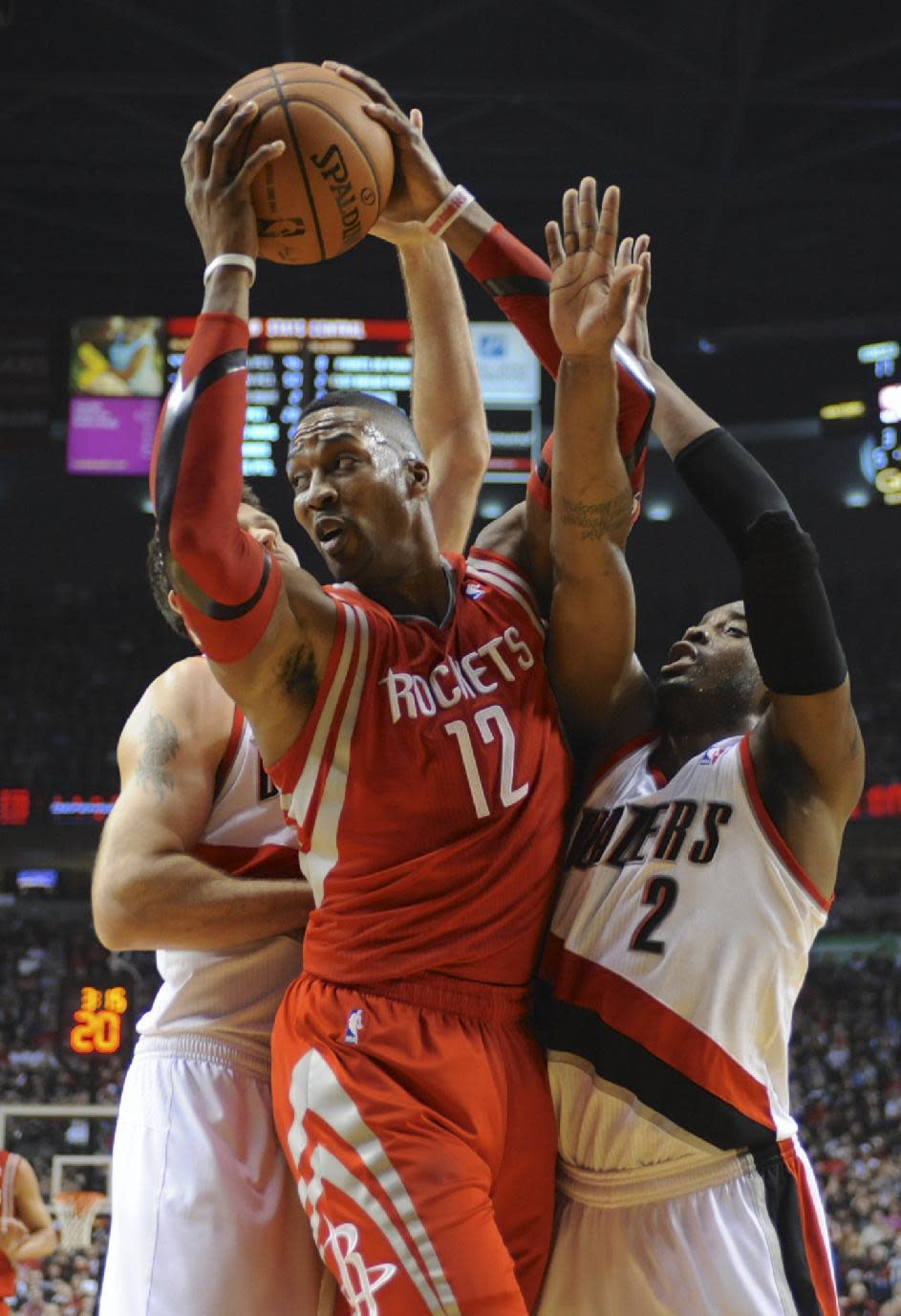 Houston Rockets' Dwight Howard (12) is trapped by Portland Trail Blazers' Wesley Matthews (2) and Joel Freeland during the first half of game four of an NBA basketball first-round playoff series game in Portland, Ore., Sunday March 30, 2014. (AP Photo/Greg Wahl-Stephens)