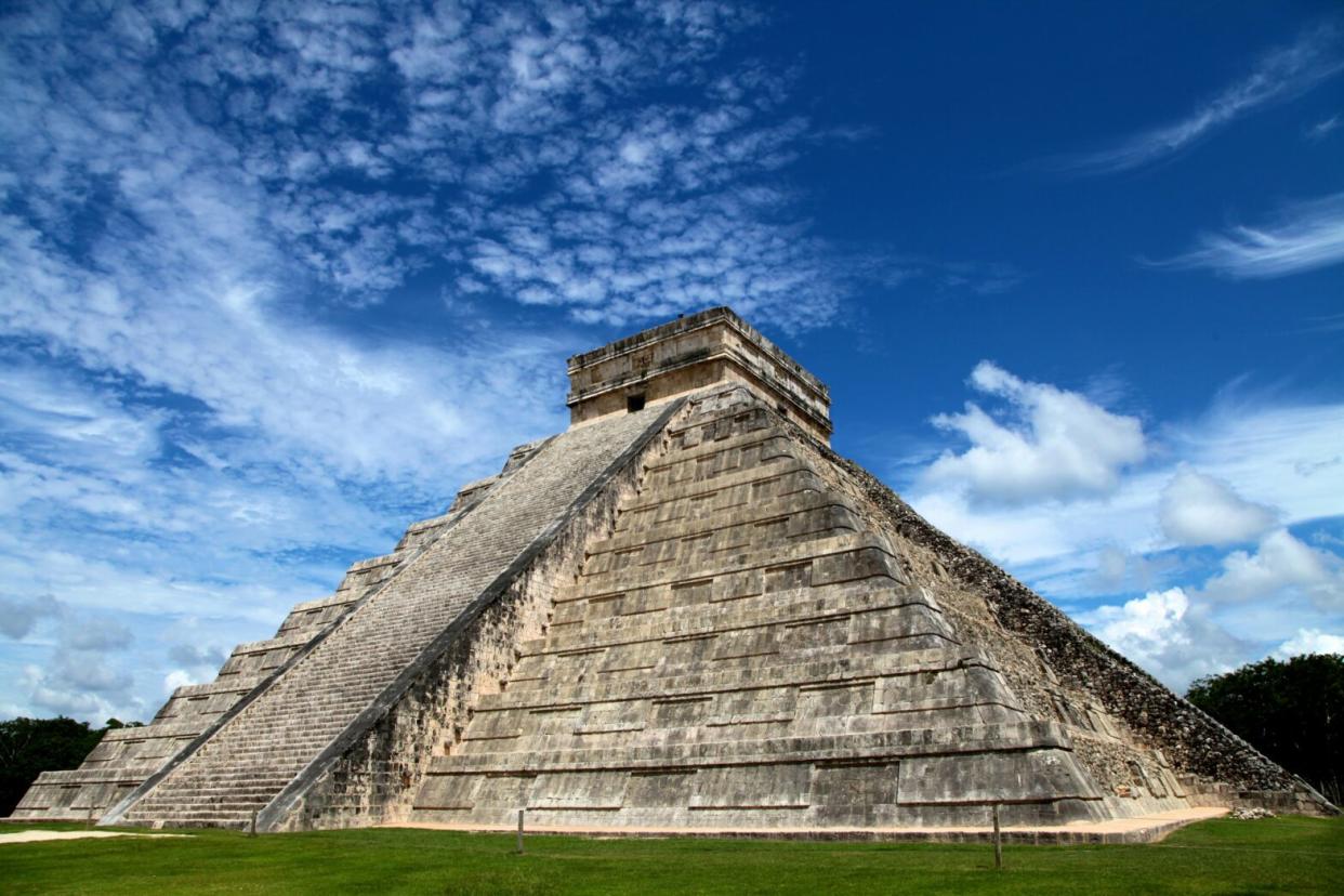 Check out the top 10 pyramids in Mexico. pictured: A grand pyramid in Mexico from below with blue skies and green grass