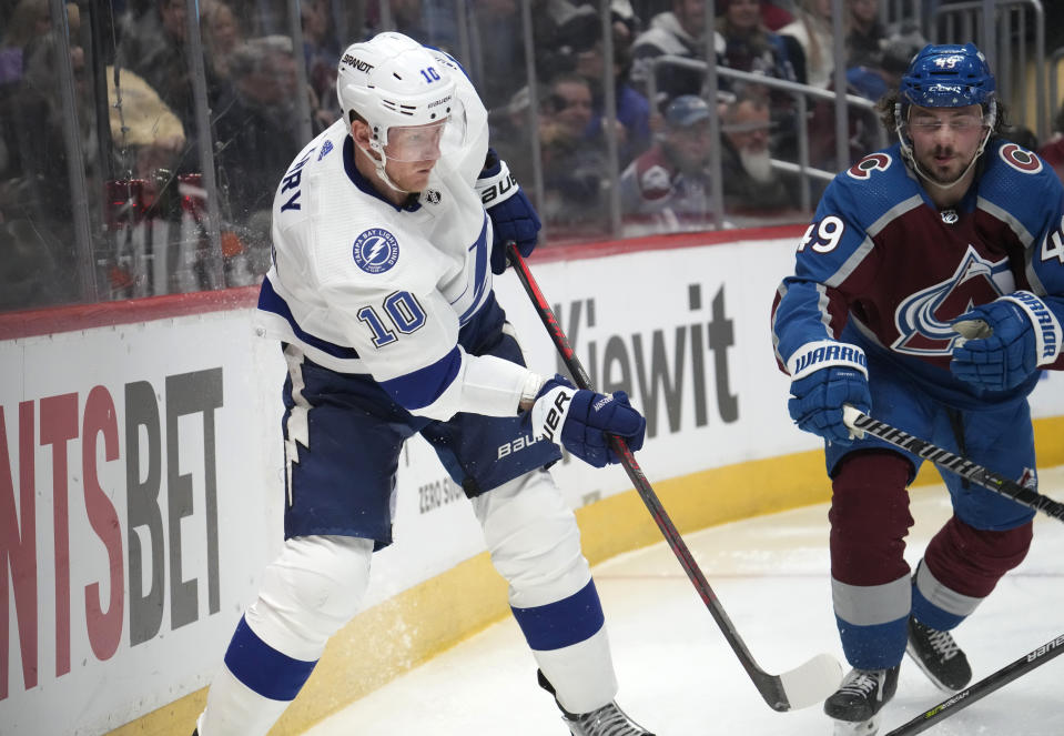 Tampa Bay Lightning right wing Corey Perry, left, passes the puck as Colorado Avalanche defenseman Samuel Girard pursues in the second period of an NHL hockey game, Tuesday, Feb. 14, 2023, in Denver. (AP Photo/David Zalubowski)