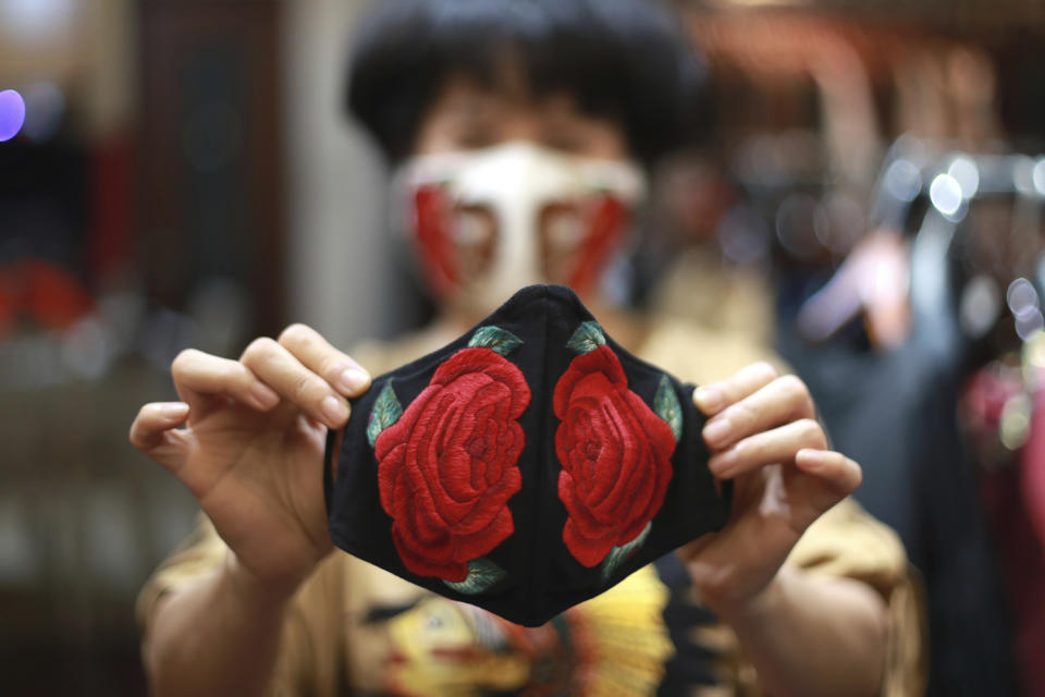 In this Wednesday, April 15, 2020, photo, fashion designer Do Quyen Hoa shows off an embroidery face mask at her studio in Hanoi, Vietnam. The collection of face masks adorned with Vietnamese hand embroideries was created as the world is fighting against the spread of the new coronavirus. (AP Photo/Hau Dinh)