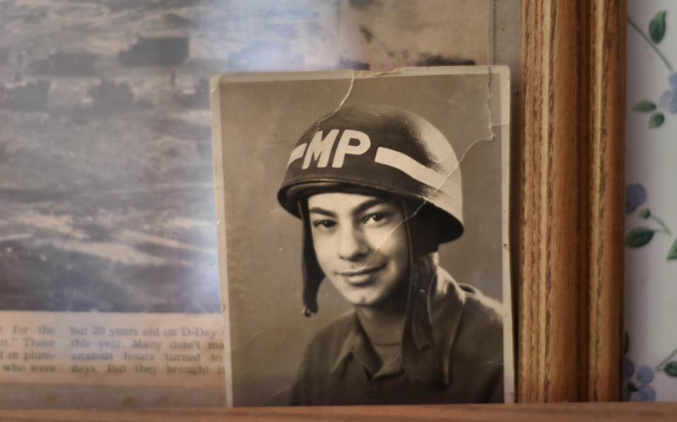 A small photo of Wampanoag Vernon Lopez, from the 1940s is tucked in the corner of a photo of the Normandy D-Day invasion hanging in his living room. The Army veteran came ashore at Omaha Beach in France and will be turning 100 next week. Steve Heaslip/Cape Cod Times