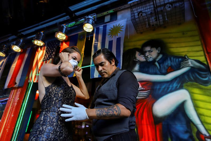 FILE PHOTO: Makrina Anastasiadou puts on a face mask before dancing with her tango partner "El Morocho" after tango shows have been suspended to prevent the spread of coronavirus (COVID-19), in Buenos Aires