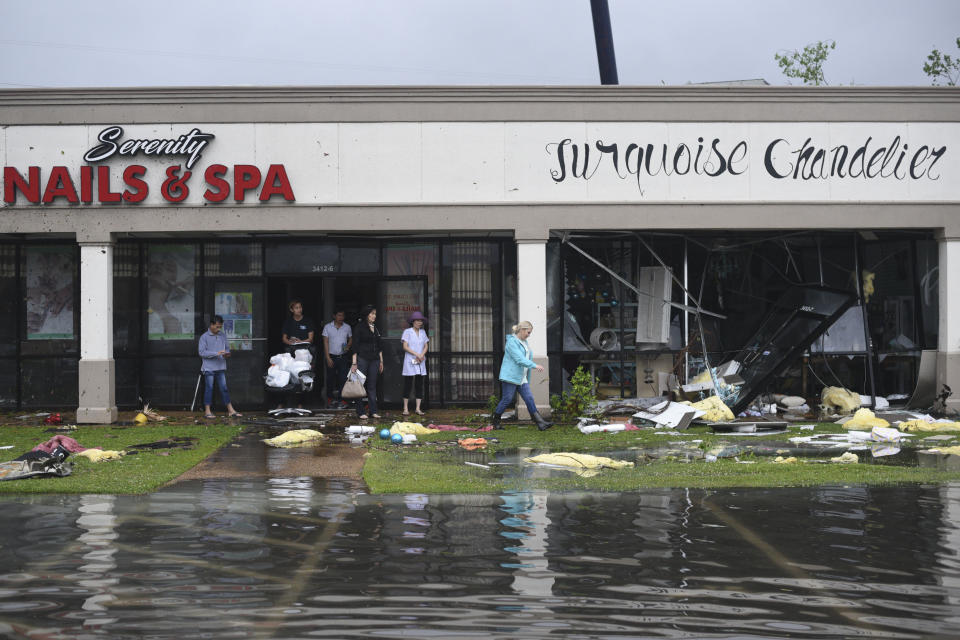 Shop owners and workers stand outside of their shops and walk amongst debris in the Pemberton Quarters strip mall following severe weather Saturday, April 13, 2019 in Vicksburg, Miss. Authorities say a possible tornado has touched down in western Mississippi, causing damage to several businesses and vehicles. John Moore, a forecaster with the National Weather Service in Jackson, says a twister was reported Saturday in the Vicksburg area of Mississippi and was indicated on radar. (Courtland Wells/The Vicksburg Post via AP)