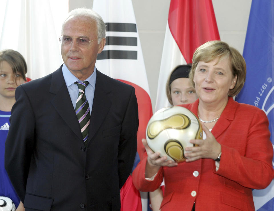 FILE - German Chancellor Angela Merkel, right, and Franz Beckenbauer, president of the local organizing committee, presents the original soccer ball for the World Cup final to young fans in Berlin Thursday, July 6, 2006. Germany's World Cup-winning coach Franz Beckenbauer has died. He was 78. Beckenbauer was one of German soccer's central figures. He captained West Germany to the World Cup title in 1974. He also coached the national side for its 1990 World Cup win against Argentina. (AP Photo/Roberto Pfeil, File)