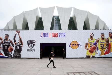 Woman walks past an entrance of the venue that was scheduled to hold fan events ahead of an NBA China game between Brooklyn Nets and Los Angeles Lakers, at the Oriental Sports Center in Shanghai,