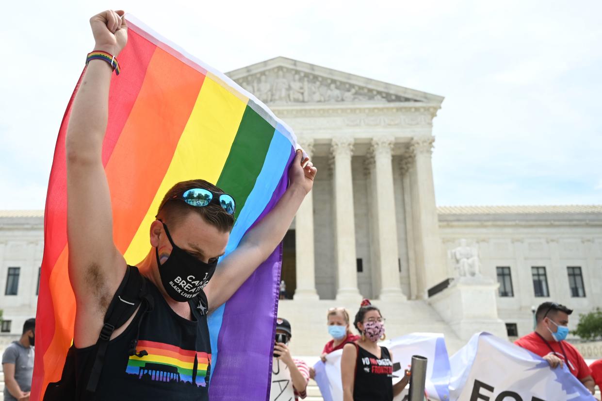 A reveler waves a rainbow flag in front of the U.S. Supreme Court that released a decision that says federal law protects LGBTQ workers from discrimination on June 15, 2020 in Washington,DC. - The US top court has ruled it illegal to fire workers based on sexual orientation. (Photo by JIM WATSON / AFP) (Photo by JIM WATSON/AFP via Getty Images)