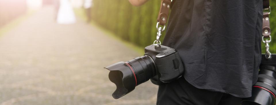 A photographer's camera hanging near their side