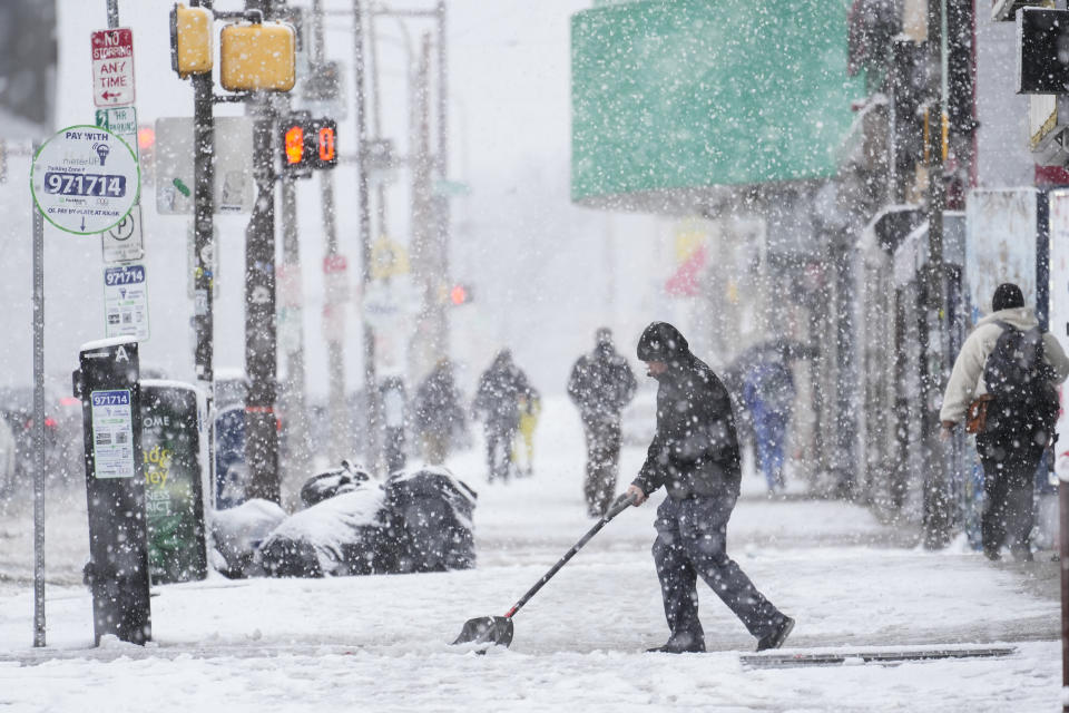 A person clears off a sidewalk during a winter snow storm in Philadelphia, Tuesday, Feb. 13, 2024. (AP Photo/Matt Rourke)