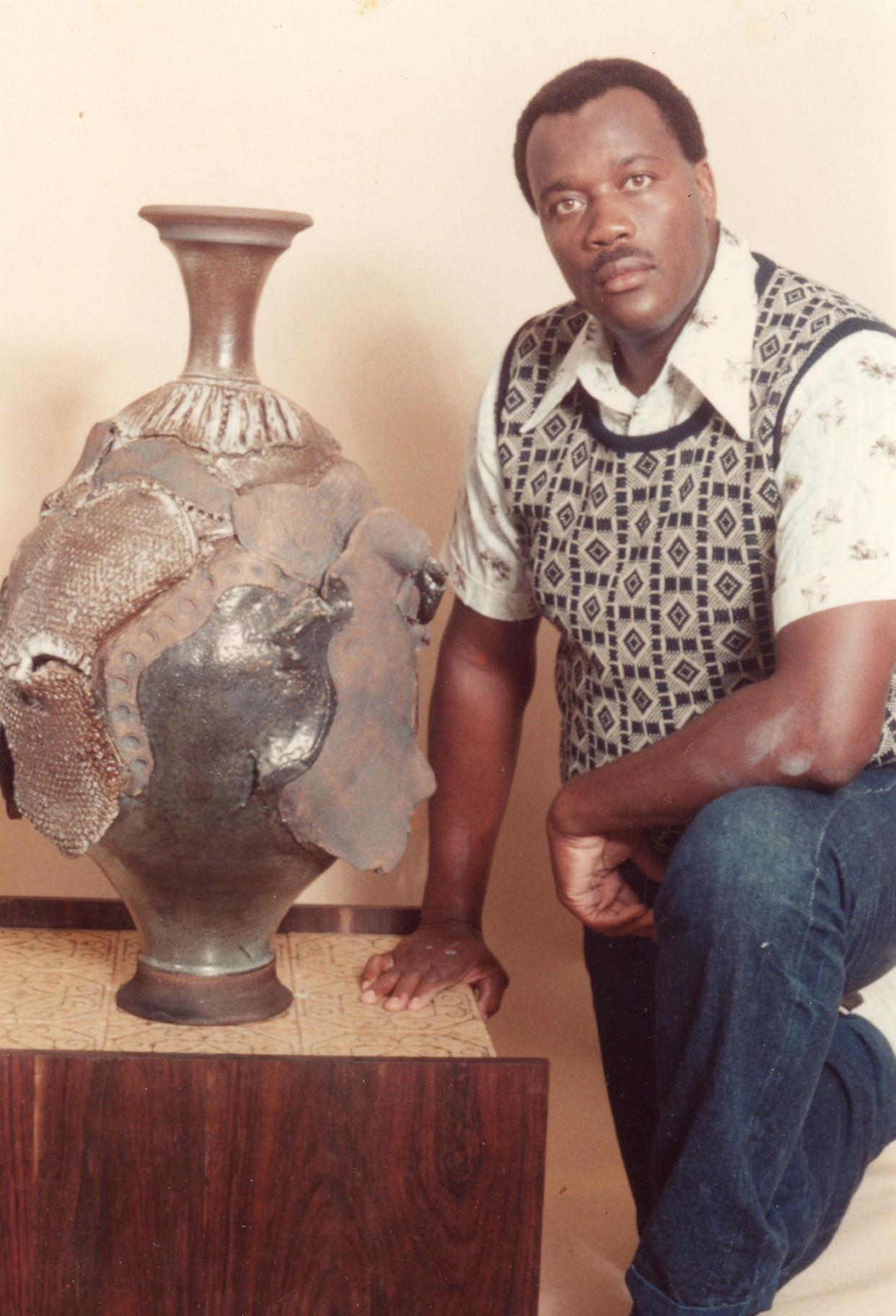 Artist Nathaniel Bustion Jr. is shown with one of his ceramic pieces.