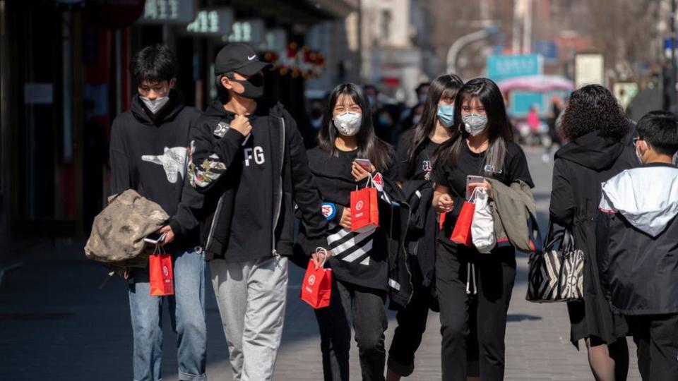 Jóvenes chinos con mascarillas.