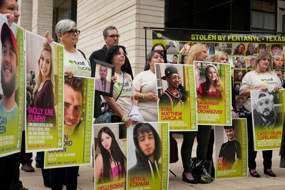 Parents and friends of people who died of fentanyl, holding posters showing their lost loved ones, attend Friday's courthouse news conference.