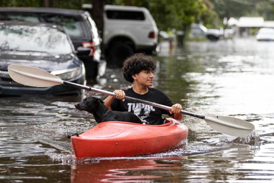 Stranahan High School student, Erick Martinez, 16, and his dog, Estrella, ride a kayak down a flooded street in his Edgewood neighborhood on Thursday, April 13, 2023, in Fort Lauderdale, Fla.