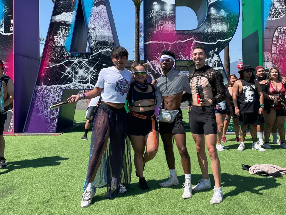 A group of four poses on green grass with large "A"and "R" block letters behind them.