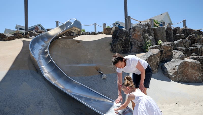 Meredith Sherwood and her daughter June Sherwood, 3, test the temperature of a slide on a hot summer day at Brookeside Park in South Jordan on Tuesday, July 2, 2024.