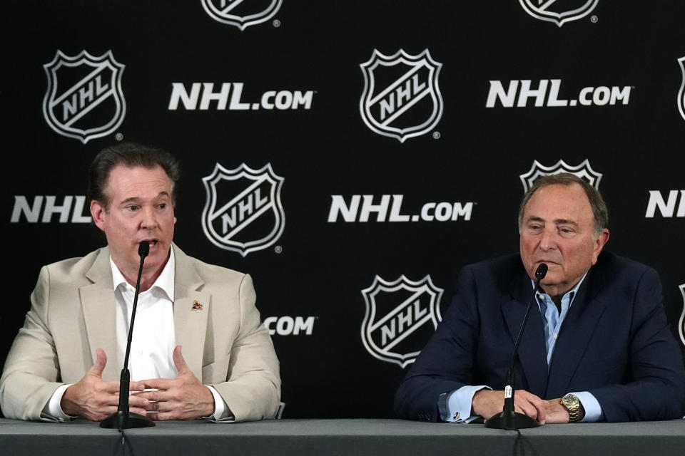 Arizona Coyotes Chairman and Governor Alex Meruelo, left, speaks as NHL Commissioner Gary Bettman, right, listens as they hold a news conference regarding a provision for Arizona to get an expansion team if a new arena is built within the next five years with the announcement of the current team relocating to Salt Lake City Friday, April 19, 2024, in Phoenix. The Coyotes are officially headed to Salt Lake City after NHL Board of Governors voted Thursday to approve a $1.2 billion sale from Meruelo to Utah Jazz owner Ryan Smith, with Meruelo retaining the Coyotes' name, logo and trademark. (AP Photo/Ross D. Franklin)