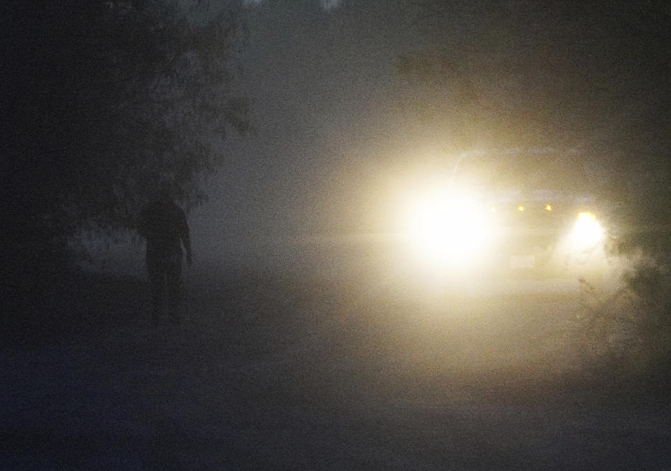 A member of the media walks on a dusty road in the dark near the site a U.S. Border Patrol and CBP and Marine Operations helicopter crash in a field just north of the Rio Grande Friday, March 8, 2024, south of La Grulla, Texas. A helicopter carrying three National Guard members and a Border Patrol agent crashed along the U.S.-Mexico border in Texas on Friday, killing three of the people on board, a county official said. (Joel Martinez/The Monitor via AP)
