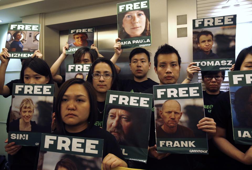 Greenpeace activists in Hong Kong carry portraits of their detained colleagues as they protest outside the Russian Consulate in Hong Kong