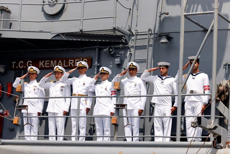 Sailors salute as they stand on a naval frigate as it is berthed at the Haifa Port