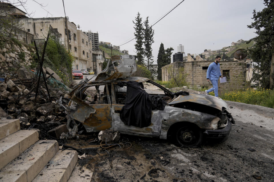 A man passes by a car destroyed in an Israeli army raid in the West Bank Jenin refugee camp on Wednesday, March 27, 2024. The Palestinian Health Ministry said early Wednesday that three Palestinians were killed and another four were wounded by Israeli fire in Jenin. (AP Photo/Majdi Mohammed)