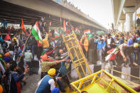 DELHI, INDIA - 2021/01/26: Protesters remove police barricades from the road during the demonstration. Farmers protesting against agricultural reforms breached barricades and clashed with police in the capital on the India's 72nd Republic Day. The police fired tear gas to restrain them, shortly after a convoy of tractors trundled through the Delhi's outskirts. (Photo by Manish Rajput/SOPA Images/LightRocket via Getty Images)