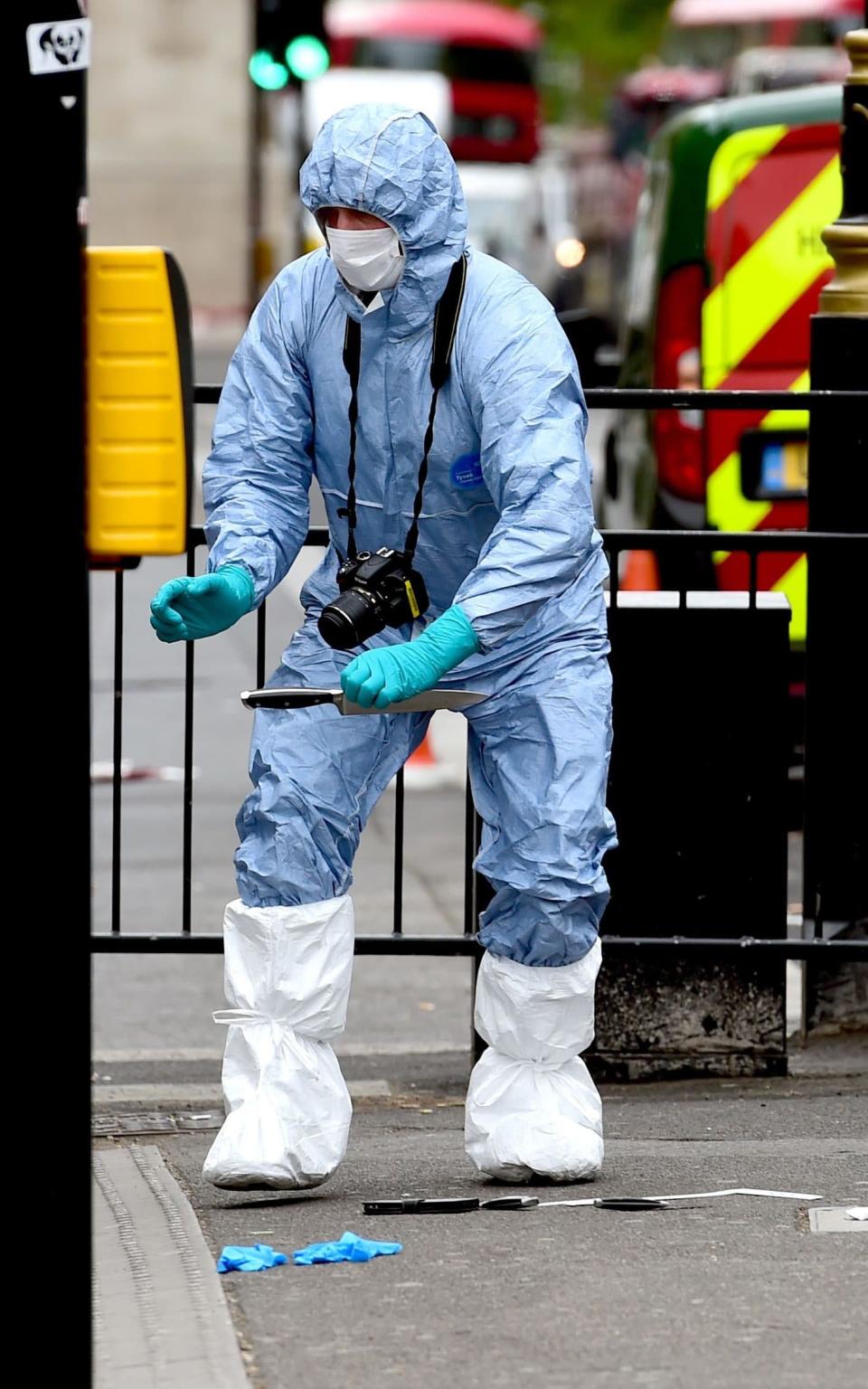 Police pick up a knife at the scene after a person was arrested following an incident in Whitehall in London.  - Credit: Lauren Hurley/PA Wire