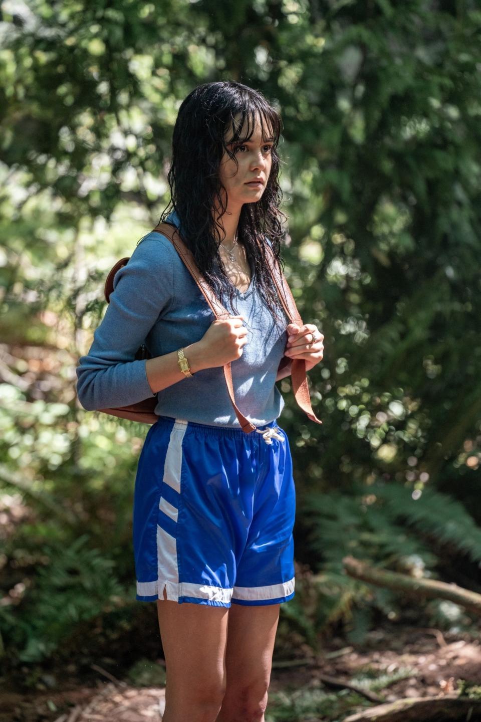 Woman in casual sportswear with a backpack looking concerned in a forest setting