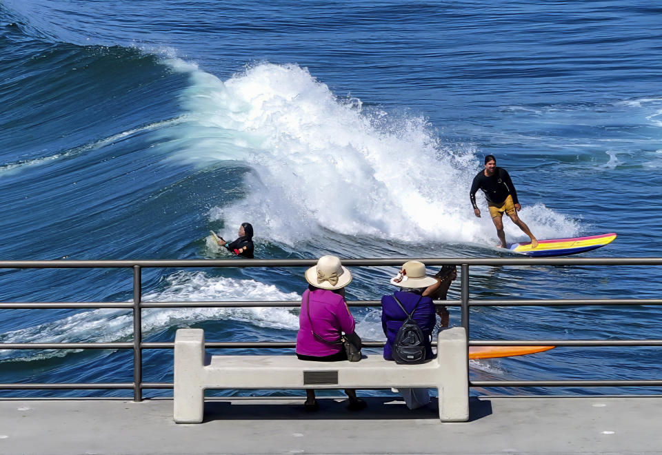ARCHIVO - Visitantes en un muelle miran a surfistas en las olas en Huntington Beach, California, el martes 19 de septiembre de 2023. (Jeff Gritchen/The Orange County Register via AP, Archivo)