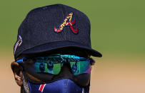 Atlanta Braves first base coach Eric Young talks, from left, Ender Inciarte, Ronald Acuna Jr., Marcell Ozuna and Ozzie Albies, Marcell Ozuna, who are reflected in his sunglasses at spring training baseball practice on Tuesday, Feb. 23, 2021, in North Port, Fla. (AP Photo/Brynn Anderson)