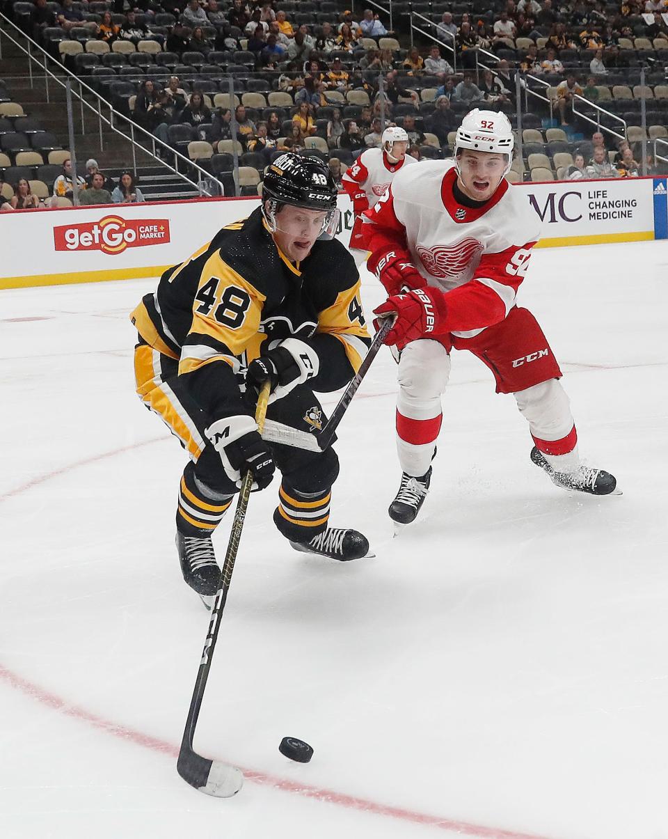 Pittsburgh Penguins right wing Valtteri Puustinen (48) reaches for the puck ahead pf Detroit Red Wings center Marco Kasper (92) during the first period at PPG Paints Arena in Pittsburgh on Wednesday, Oct. 4, 2023.
