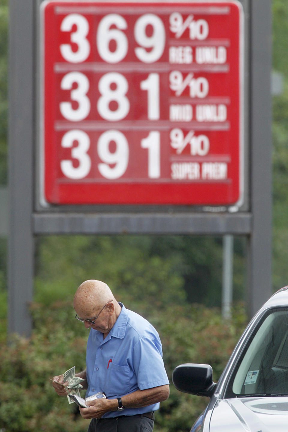 George Matkowski, of Montpelier, reaches into his wallet to pay for gas, Friday, Aug. 10, 2012, in Montpelier, Vt. A rise in the price of crude oil and problems with refineries and pipelines in the West Coast and Midwest have caused prices at the pump to surge upward. (AP Photo/Toby Talbot)