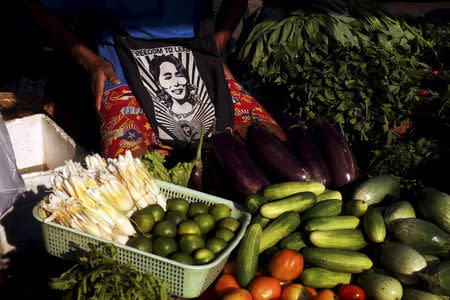 A vendor carrying a bag with a picture of Aung San Suu Kyi sells vegetables in downtown Yangon April 3, 2015. REUTERS/Minzayar