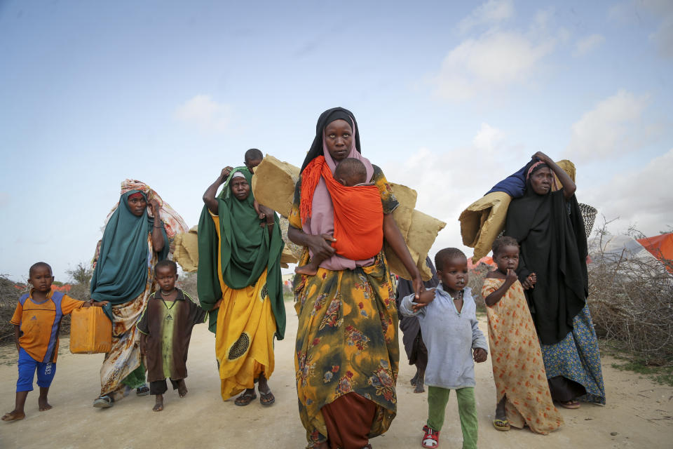 Somalis who fled drought-stricken areas carry their belongings as they arrive at a makeshift camp for the displaced on the outskirts of Mogadishu, Somalia Thursday, June 30, 2022. The war in Ukraine has abruptly drawn millions of dollars away from longer-running humanitarian crises and Somalia is perhaps the most vulnerable as thousands die of hunger amid the driest drought in decades. (AP Photo/Farah Abdi Warsameh)