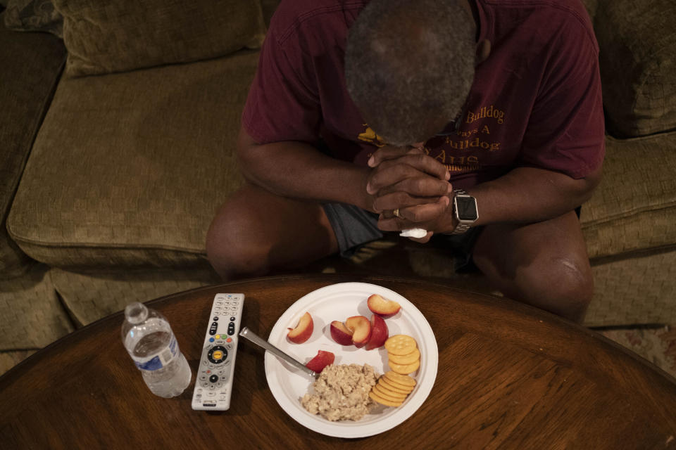 Mike Bishop prays before his dinner in front of the television in his living room in Byram, Miss., on Thursday, Oct. 8, 2020. He's hoping his wife, Bonnie Bishop, will be back by Thanksgiving. (AP Photo/Wong Maye-E)