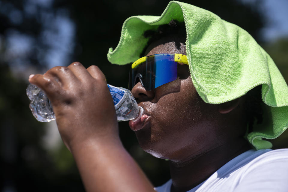 FILE - Amir Brown, 15, tries to cool down while helping his mother set up a stand selling cold drinks near the National Mall on July 22, 2022, in Washington. The Biden Administration Tuesday, July 26, unveiled a new website, heat.gov, that federal officials hope can help people and local governments beat the heat and keep it from getting deadly. (AP Photo/Nathan Howard, File)