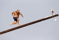 RNPS - PICTURES OF THE YEAR 2013 - A man runs up the "gostra", a pole covered in grease, during the religious feast of St Julian, patron of the town of St Julian's, outside Valletta August 25, 2013. In the traditional "gostra", a game stretching back to the Middle Ages, young men, women and children have to make their way to the top and try to uproot one of the flags to win prizes. From May to September in Malta, there is hardly any weekend when a town or a village is not celebrating the feast of its patron saint or other saints revered in different churches. REUTERS/Darrin Zammit Lupi (MALTA - Tags: RELIGION SOCIETY TRAVEL TPX) MALTA OUT. NO COMMERCIAL OR EDITORIAL SALES IN MALTA