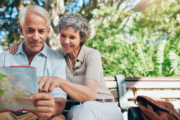 Older couple on a park bench looking at a map