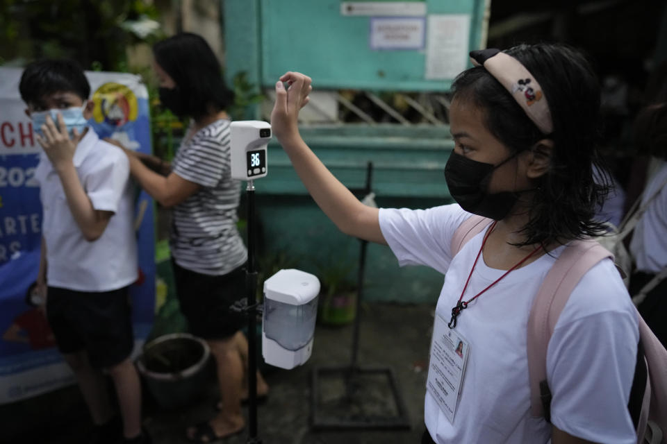 A student checks her temperature during the opening of classes at the San Juan Elementary School in metro Manila, Philippines on Monday, Aug. 22, 2022. Millions of students wearing face masks streamed back to grade and high schools across the Philippines Monday in their first in-person classes after two years of coronavirus lockdowns that are feared to have worsened one of the world's most alarming illiteracy rates among children. (AP Photo/Aaron Favila)