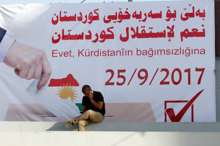 A man talks on the phone infront of a banner urging people to vote for the 25th independence referendum in Kirkuk, Iraq September 10, 2017. REUTERS/Ako Rasheed