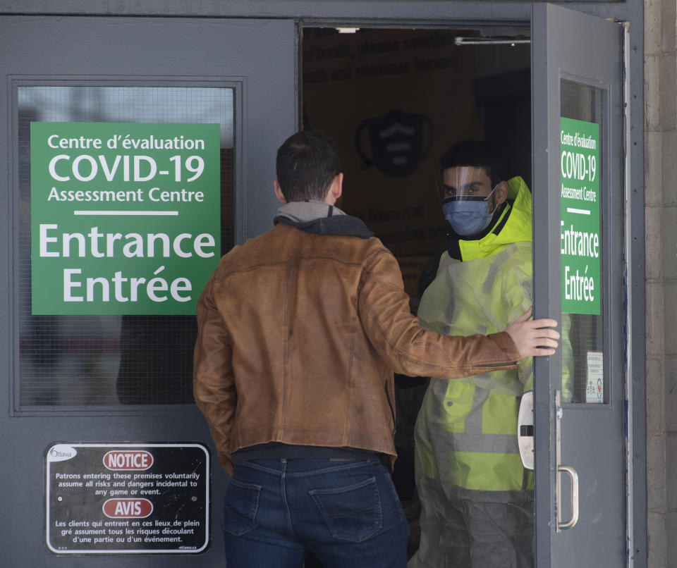 A security guard opens the door for a person entering a COVID-19 assessment facility, Saturday, March 14, 2020 in Ottawa. For most people, the new coronavirus causes only mild or moderate symptoms. For some it can cause more severe illness, especially in older adults and people with existing health problems. (Adrian Wyld/The Canadian Press via AP)