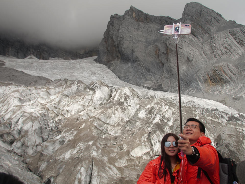 This Sept. 22, 2018 photo shows tourists posing for a selfie before the Baishui Glacier No.1 atop of the Jade Dragon Snow Mountain in the southern province of Yunnan in China. Scientists say the glacier is one of the fastest melting glaciers in the world due to climate change and its relative proximity to the Equator. It has lost 60 percent of its mass and shrunk 250 meters since 1982. (AP Photo/Sam McNeil)