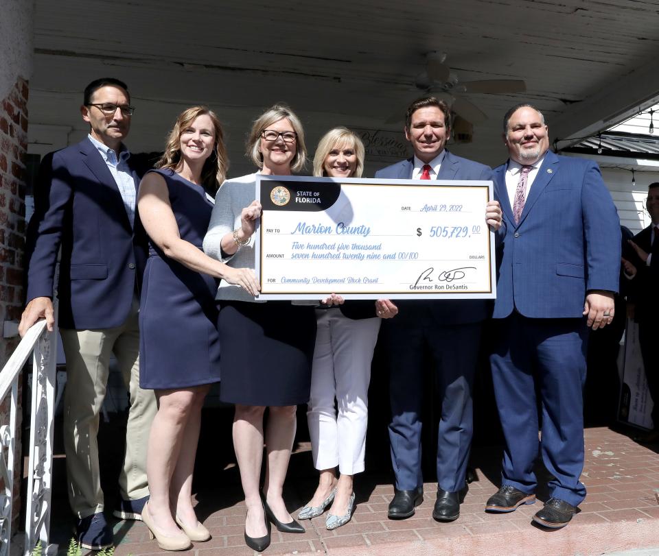 Gov. Ron DeSantis poses with Marion County officials and a large check for over $500,000 for infrastructure improvements in the county, on the front porch of the Ivy House Restaurant in Williston on April 29, 2022.