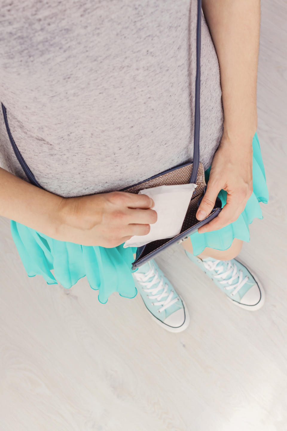 Young stylish woman putting hygiene pad in handbag